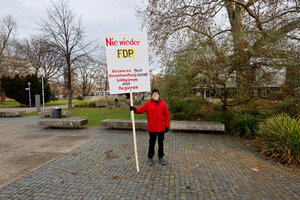 Einsamer Mann mit rotem Anorak hält ein Schild 