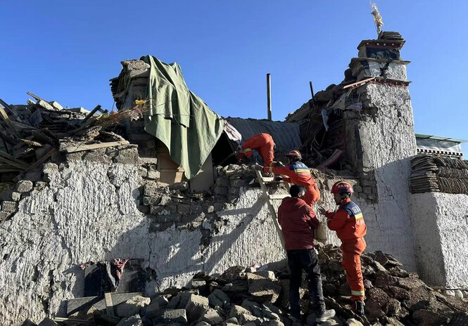 Rettungskräfte gelangen über eine Leiter in die Ruine eines halbeingestürzten Gebäudes