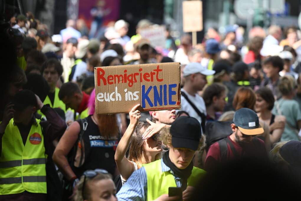 Demonstranten gehen auf die Strasse gegen die AfD am Samstag, dem 28. Juni 2024. Eine Protestierende hält ein Schild, auf dem steht: "Remigriert Euch ins Knie"