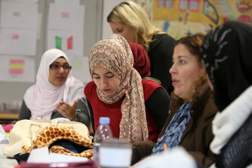 Frauen mit Kopftüchern sitzen beieinander und reden