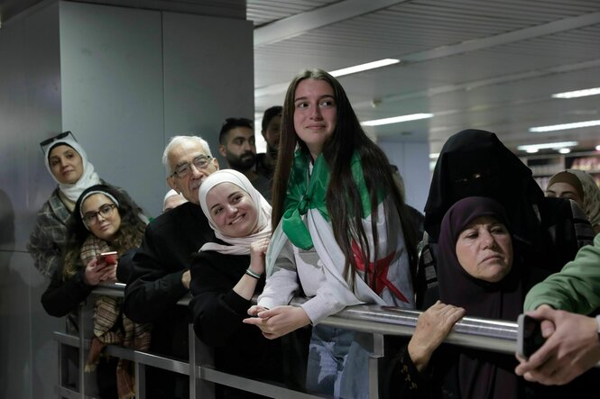 Menschen warten freudig aufn einer Flughafenabsperrung