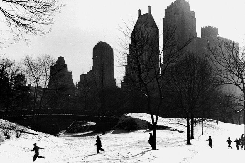 Kinder laufen vor Hochhäusern im SChnee im Central Park