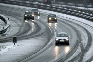 Autos fahren über eine verschneite Straße.