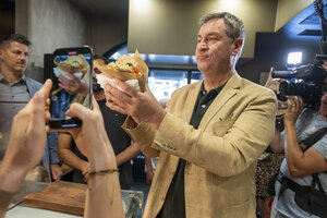 Markus Söder präsentiert Fotografen in einem Dönerlokal einen frischen Döner.