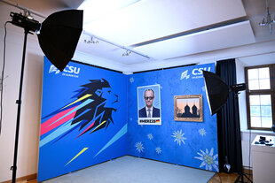 Eine blau-weiße Stellwand mit dem CSU-Logo und einem Foto von Friedrich Merz mit Sonnenbrille