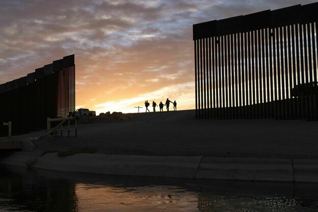 Silhoutten von einer Familie vor dem Grenzzaun in Mexico