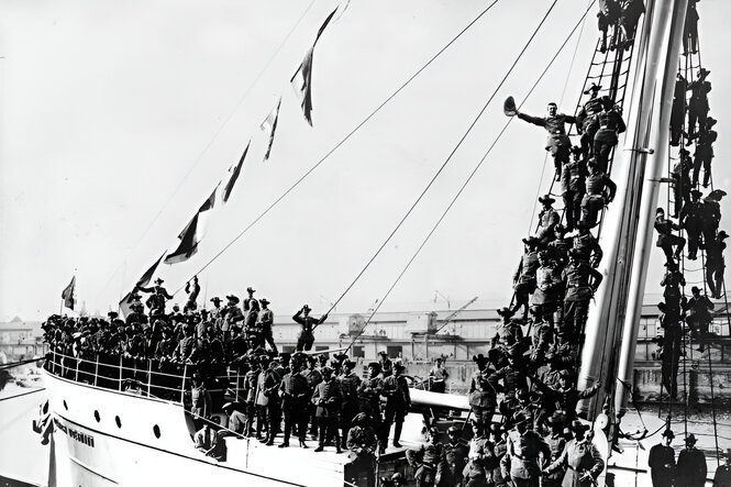 Soldaten stehen auf einem Schiff und winken zum Abschied.