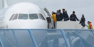 Menschen stehen auf einer Gangway an einem Flugzeug