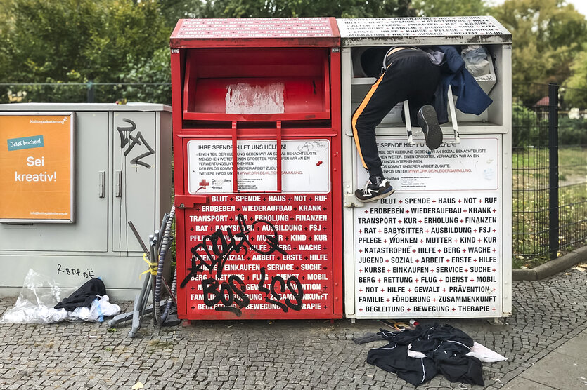 Eine Person klettert in einen Altkleidercontainer.