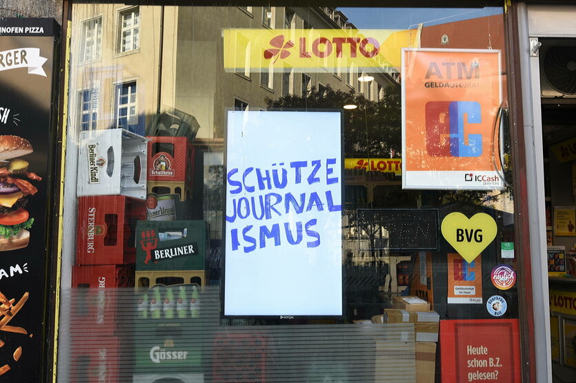 In einem Schaufenster hängt eine Protestschild mit der Aufschrift: SCHÜTZE JOURNALISMUS