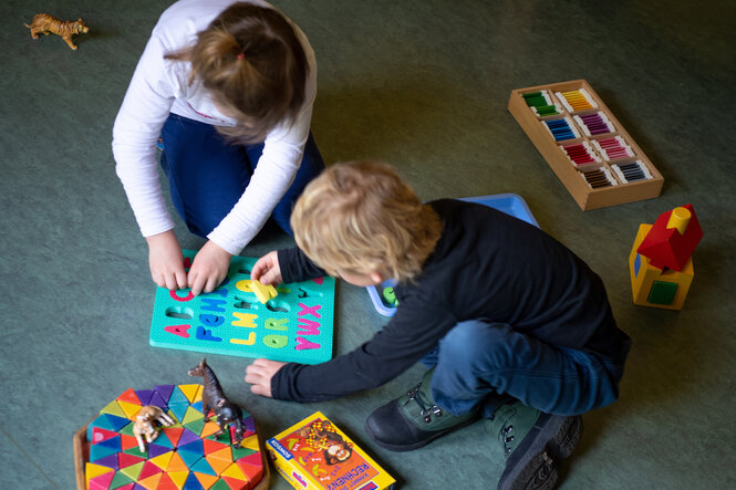 Ein Junge und ein Mädchen spielen in einem Kindergarten auf dem Boden.