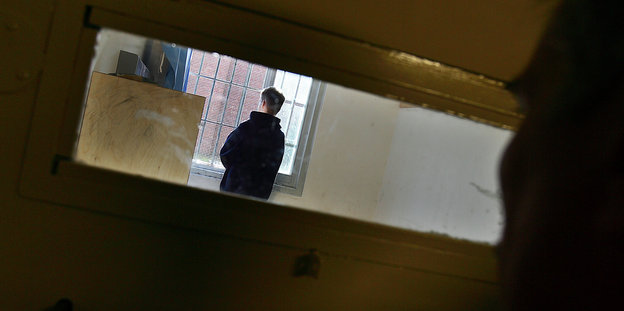 Ein junger Mann steht in einer Gefängniszelle