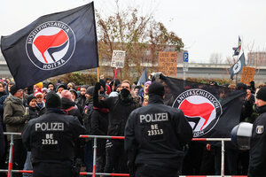 Antifa-Banner und Demonstrierende, davor Polizisten von hinten