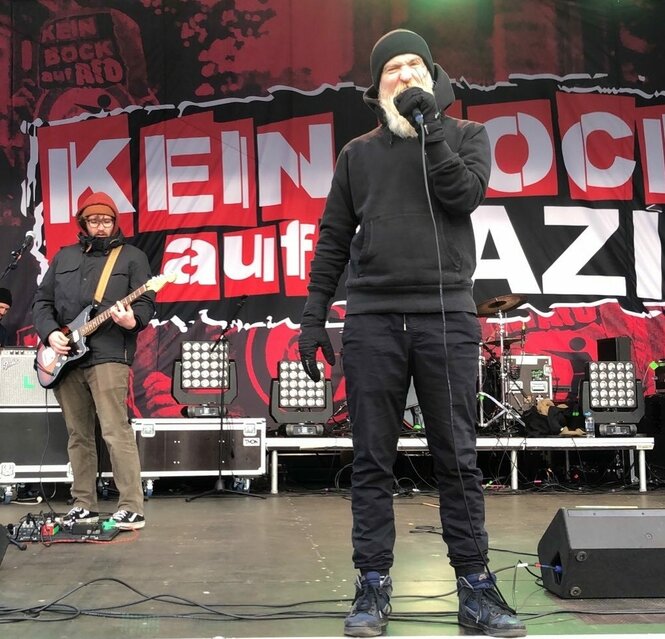 2 Musiker von der Band Team Scheiße und Antifa-Transpi im Hintergrund