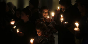 Frauen und Kinder halten Kerzen in den Händen