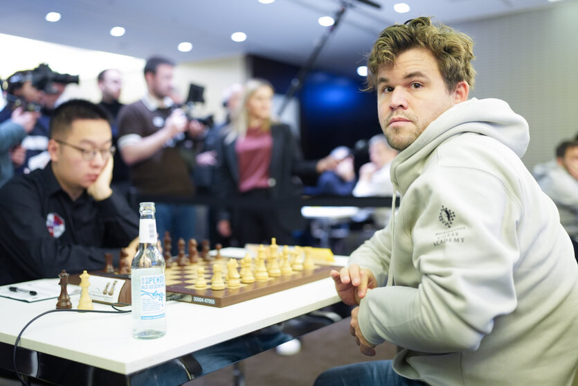 Magnus Carlsen und Gegner am Tisch sitzend vorm Schachbrett