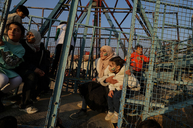 Frauen und Kinder sitzen auf der Schaukel eines alten Vergnügungsparks in der Sonne