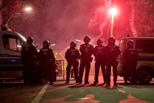 Auf dem Bild stehen EInsatzkräfte udn Polzeiwagen vor eine Roten SIlvesterrakete