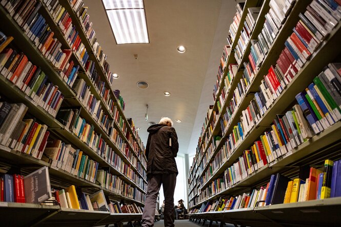 Mensch zwischen Bücherregalen