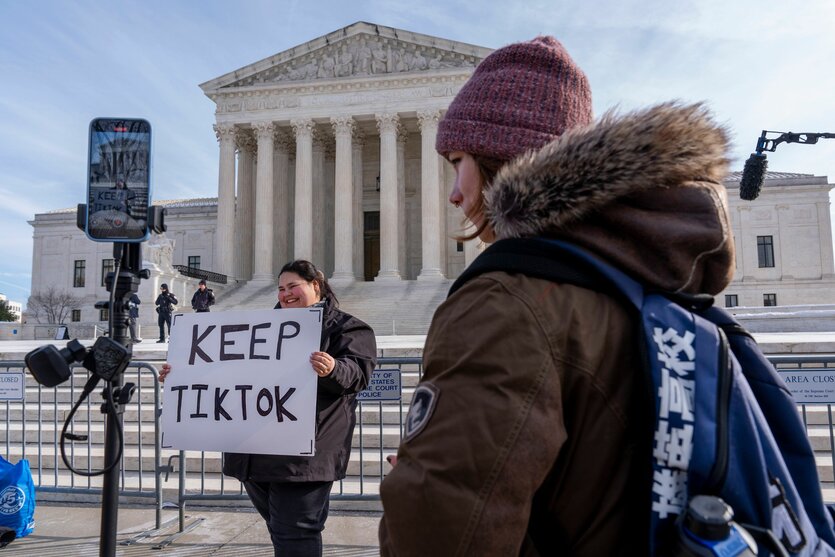 Tiktok-User vor dem Obersten Gerichtshof der USA, eine mit einem Schild, auf dem "Keep Tiktok" steht. Im Vordergrund ein filmendes Handy auf einem Aufsteller.