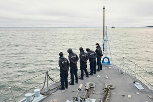 Soldaten schauen von einem Schiff aus auf Wasser