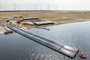 Schwimmende Soalranlage auf einem See, im Hintergrund Windanlagen