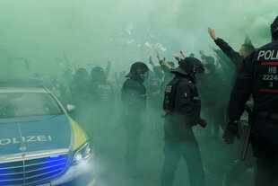 Behelmte Polizisten mit Fußballfans.