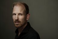 Rutger Bregman trägt ein dunkles Hemd und einen Bart