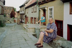 mehrere menschen sitzen vor ihren häusern