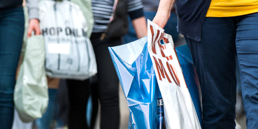 Kunden tragen Plastiktüten verschiedener Geschäfte.