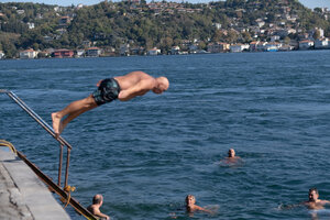 Ein äterer Mann springt kopfüber in den Bosporus, unten erwarten ihn Schwimmer