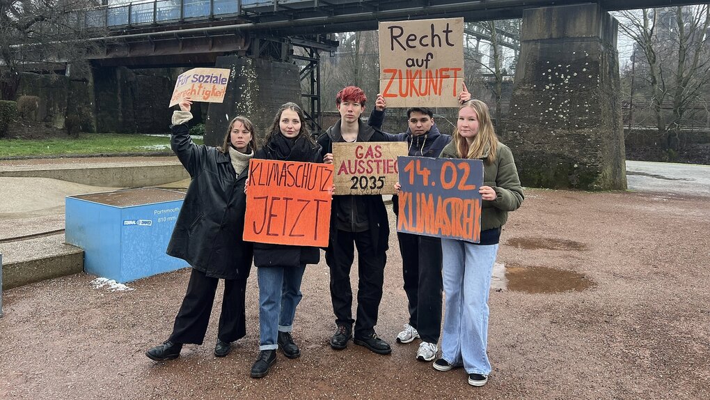 Protestierende posen mit Plakaten vor der Presse.