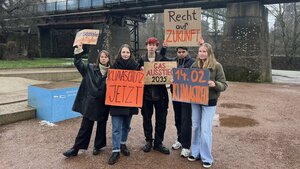 Protestierende posen mit Plakaten vor der Presse.