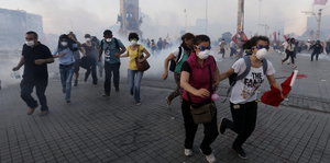 Menschen mit Masken rennen vor Tränengas davon