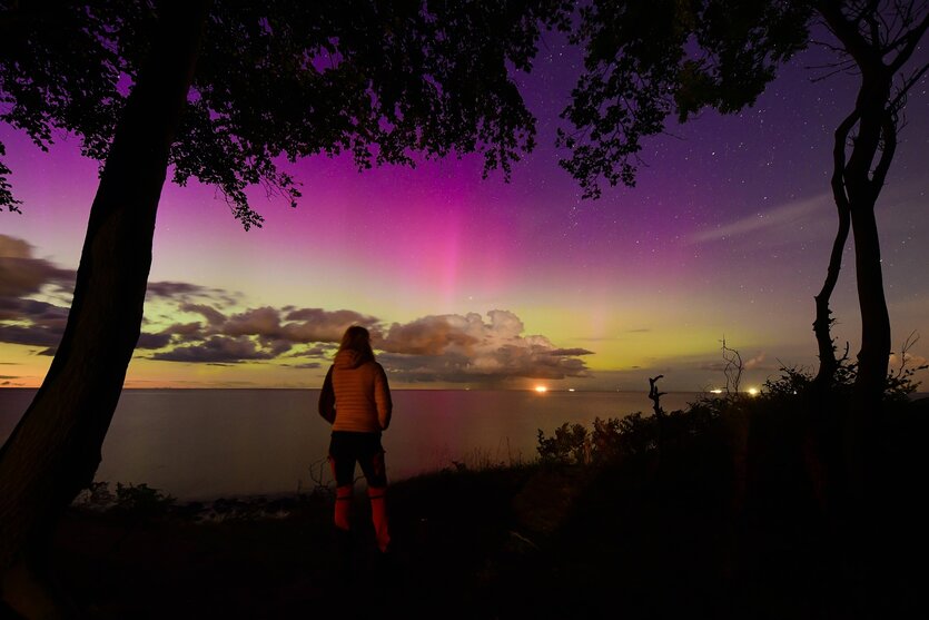 Eine Frau schut in einen bunt gefärbten Himmel