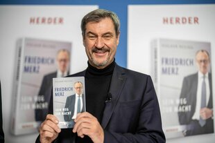 Markus Söder hält ein Buch in den Händen