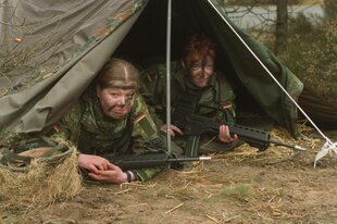 Zwei Soldatinnen schauen mit Gewehr aus einem Zelt