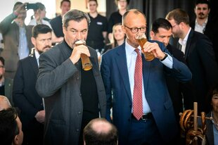 Markus Söder und Friedrich Merz trinken gemeinsam Bier