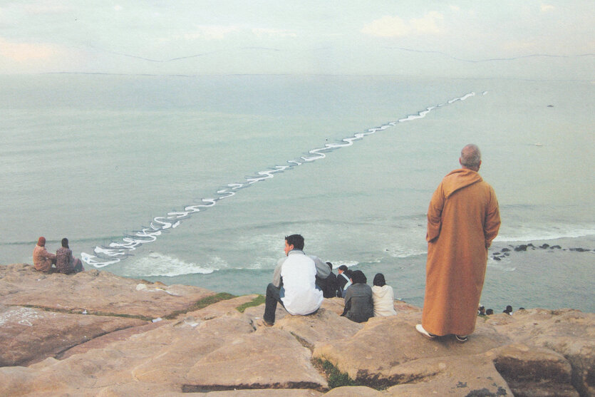 Menschen schauen von einem Felsen aus aufs Meer