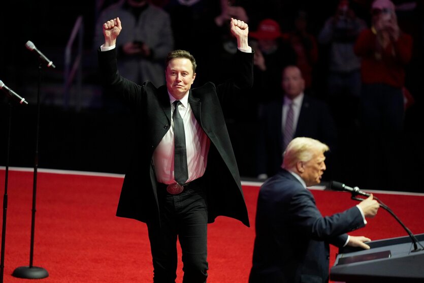 Donald Trump steht am Redepult, Elon Musk reckt die Arme hoch