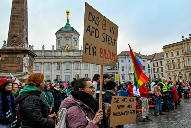 Menschen demonstrieren mit Regenbogenfahnen und Plakaten, auf einem steht "Das B in AfD steht für Bildung"