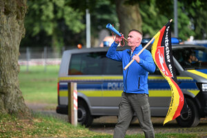 Andreas Iloff mit Fahne und Tröte, im Hintergrund ein Polizeifahrzeug