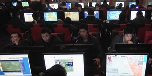 Mehrere junge Menschen sitzen in China in einem Interncafé
