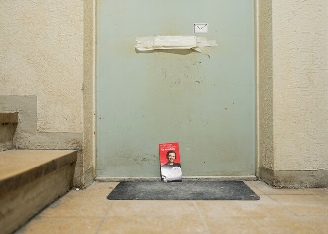 Ein roter Werbeflyer der SPD lehnt an einer Wohnungstür