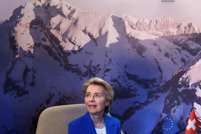 Ursula von der Leyen sitzt vor einer Wand, auf der ein Bergtableau abgebildet ist