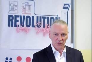 Oliver Nöll vor einem Poster mit dem Wort "Revolution"