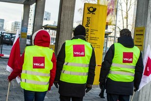 Drei Personen mit ver.di-Westen vor einer Postzentrale in München