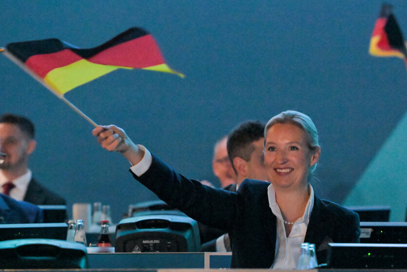 Alicwe Weidel schwenkt eine kleine Deutschland Flagge mit ausgestrecktem rechten Arm auf dem Parteitag