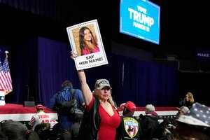 Typisch amerikanische Wahlkampfveranstaltung von Donald Trump, noch ist es ruhig eine weiblich gelesene Person hält ein Schild in die auf dem ein Bild von Laken Riley ist und 