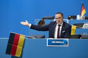 Tino Chrupalla sitzt beim Bundesparteitag der AfD in Riesa, redet und streckt den rechten Arm nach rechts.